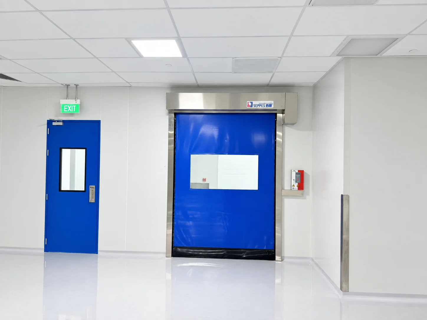 SEPPES blue cleanroom high speed door with a vision panel beside a personnel entrance