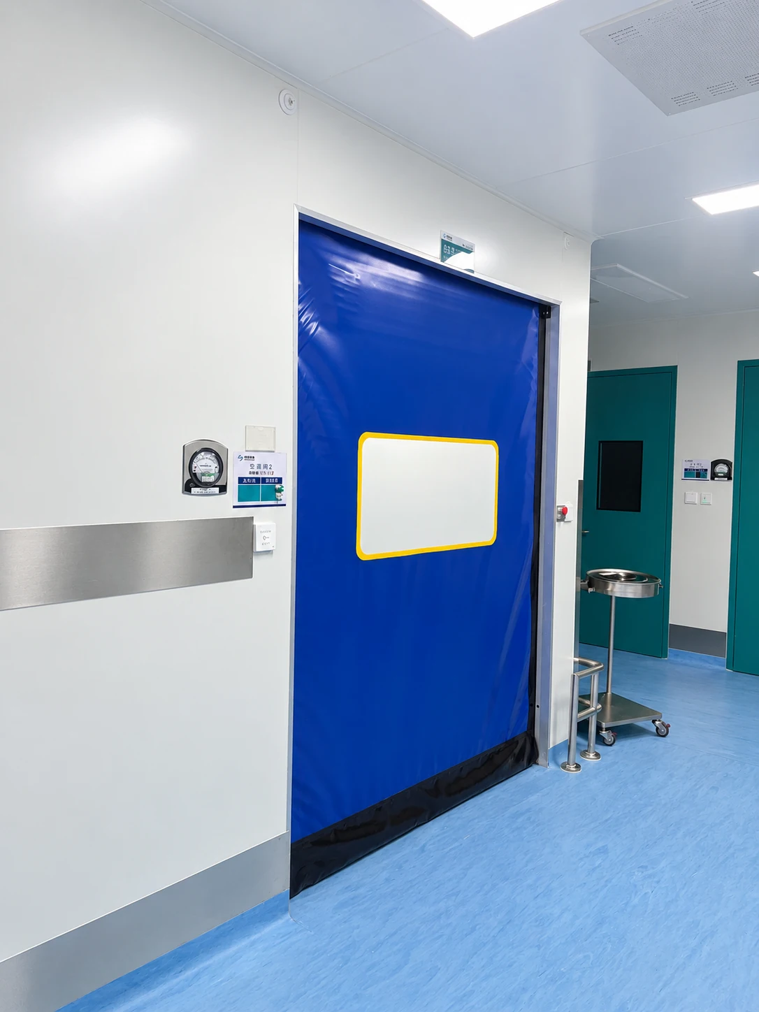 Retouched installation photograph of a blue cleanroom door beside a room pressure gauge